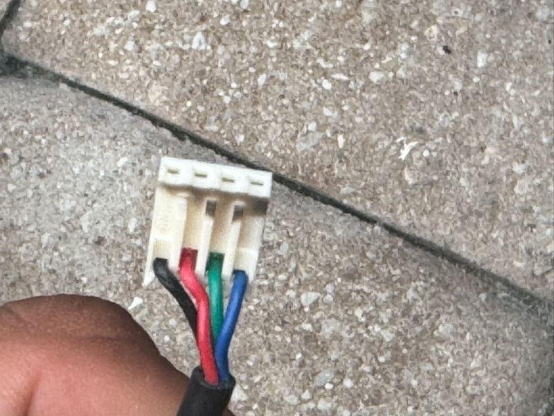 Small white connector with red, black, and blue wires on a concrete surface