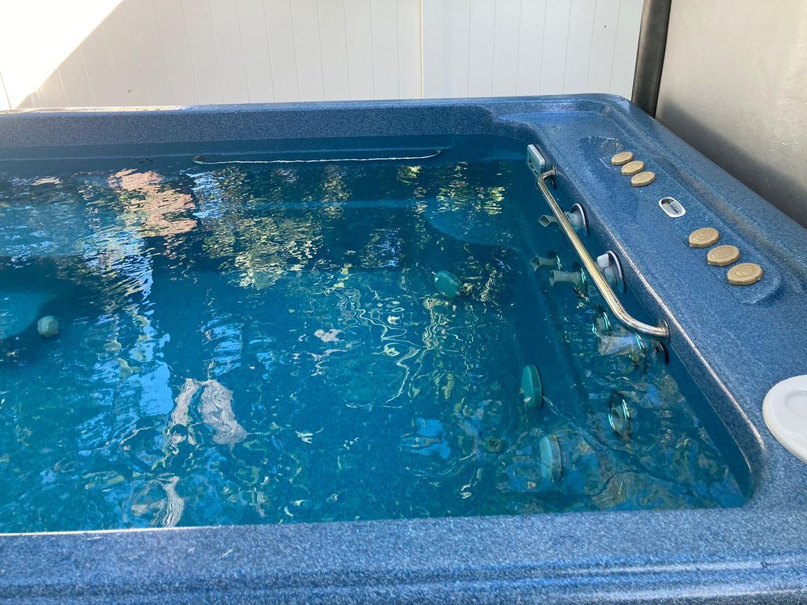 Blue hot tub filled with water, buttons on the side.