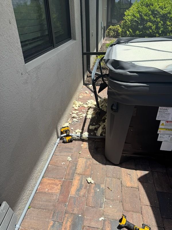 Damaged brick walkway beside a house and grill, with scattered debris and a yellow toy truck.