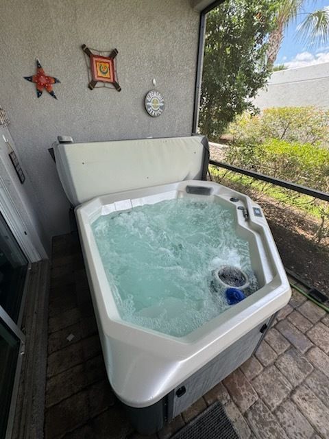 Outdoor hot tub on a patio, filled with bubbling water near a railing and wall decorations