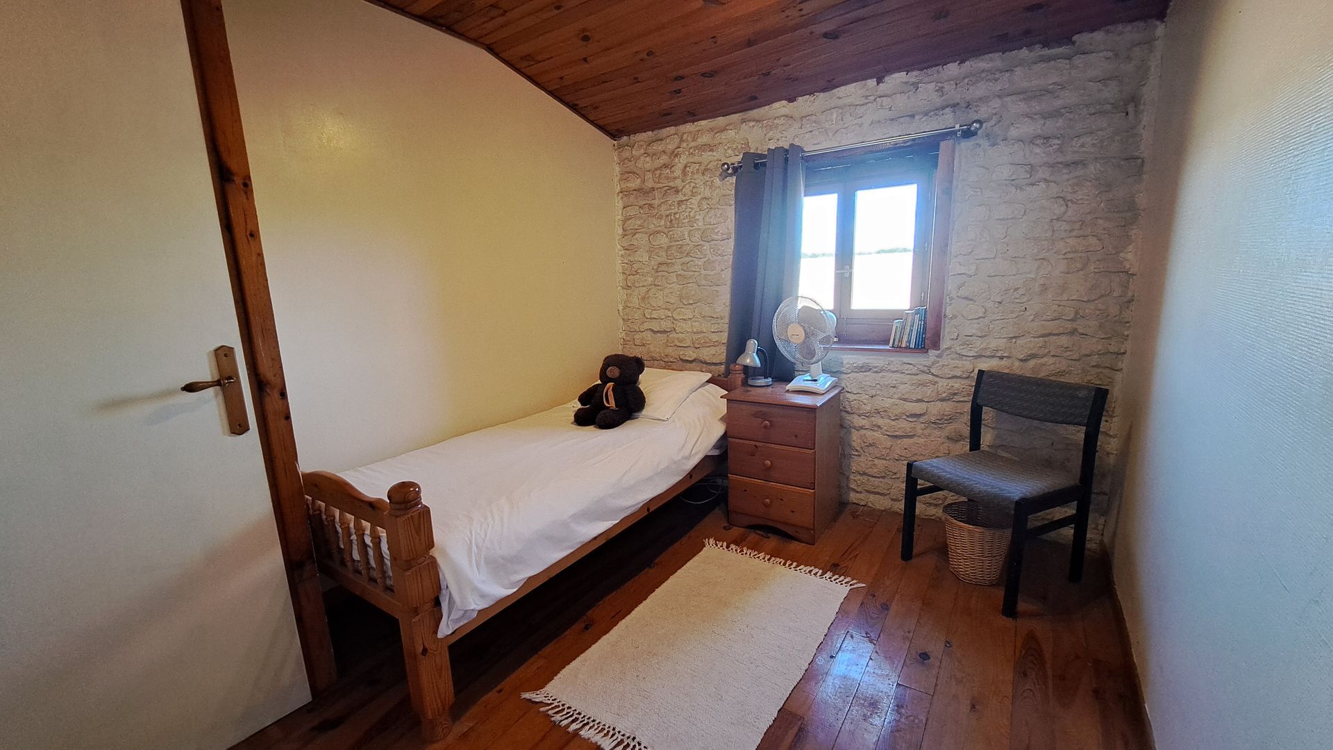 single pine bed with pine bedside table, in a bedroom with pine floorboards