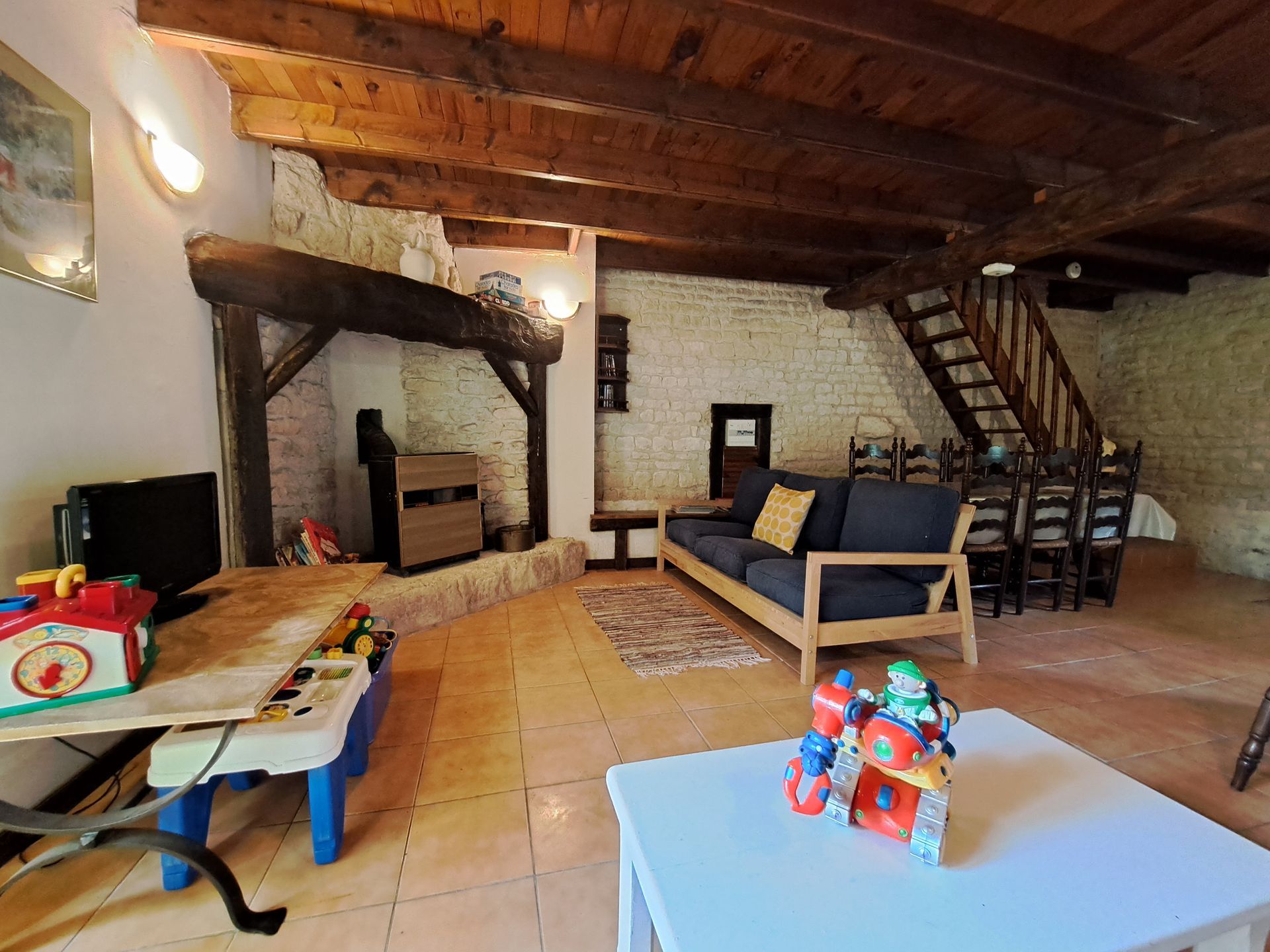 Sitting room in a stone holiday cottage with open slatted wooden stair case and childrens toys in the foreground