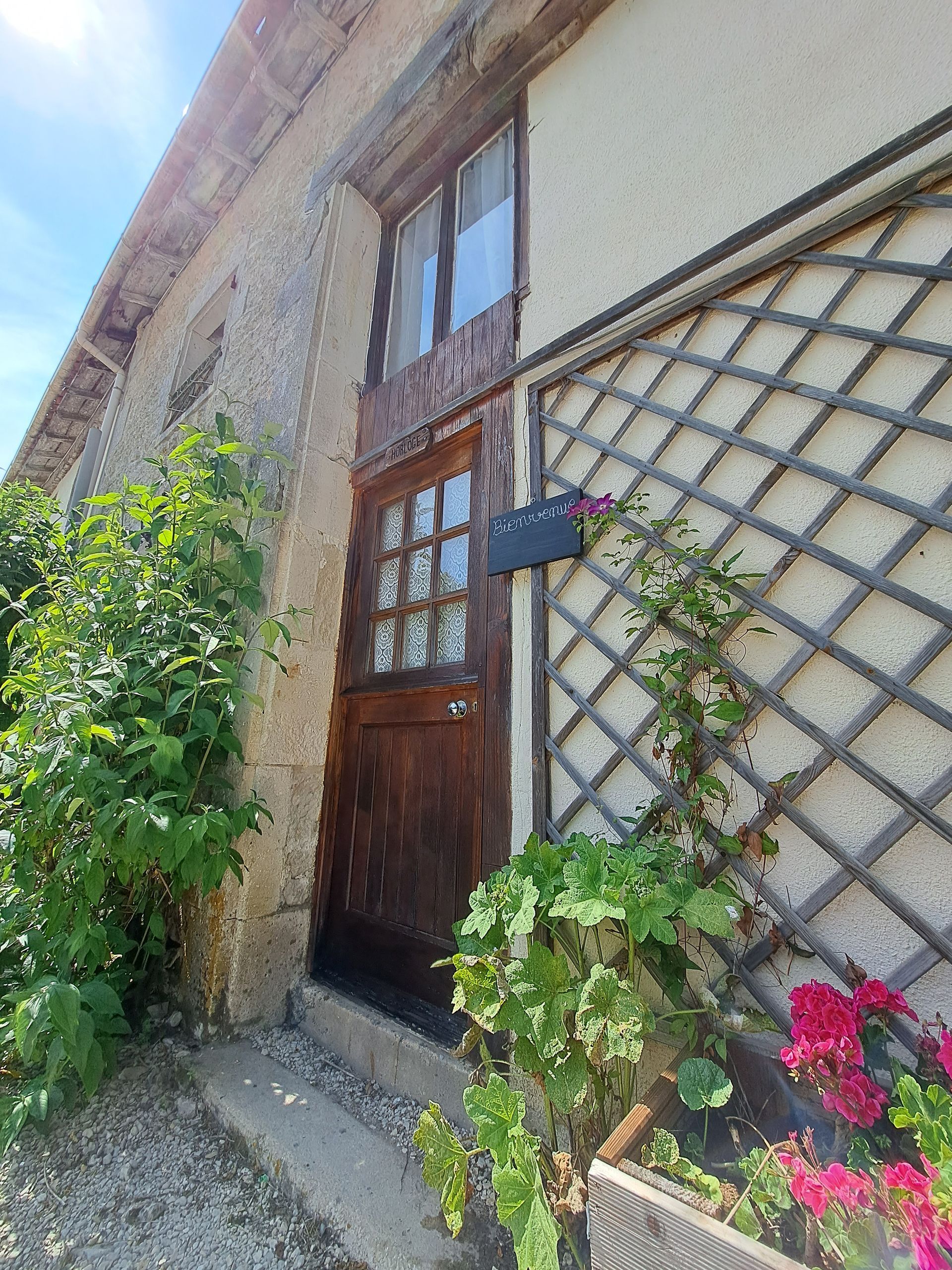 wooden front door with a trellis next to it