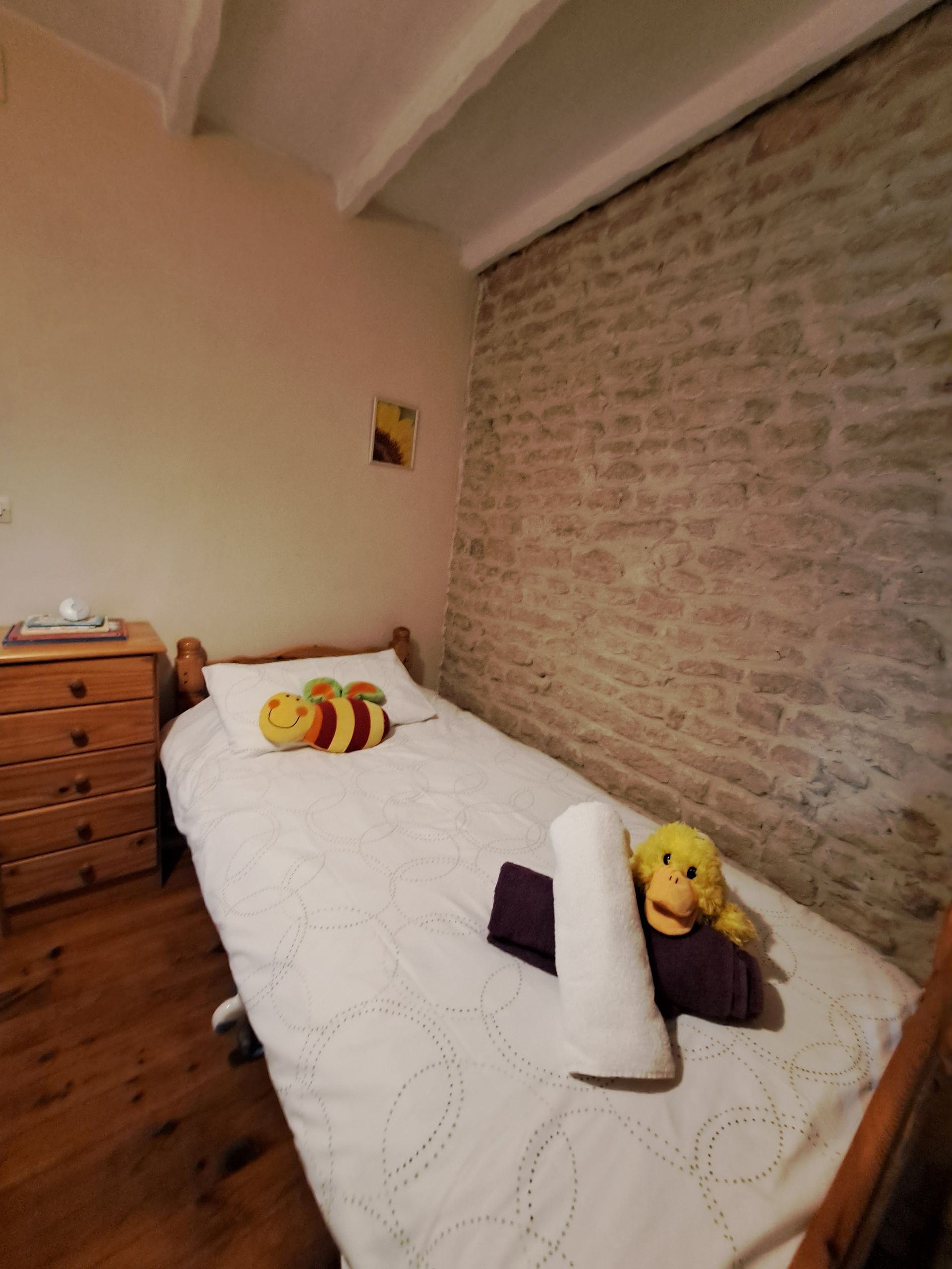 lit simple pour enfants avec peluches dans une chambre avec un mur en pierre
