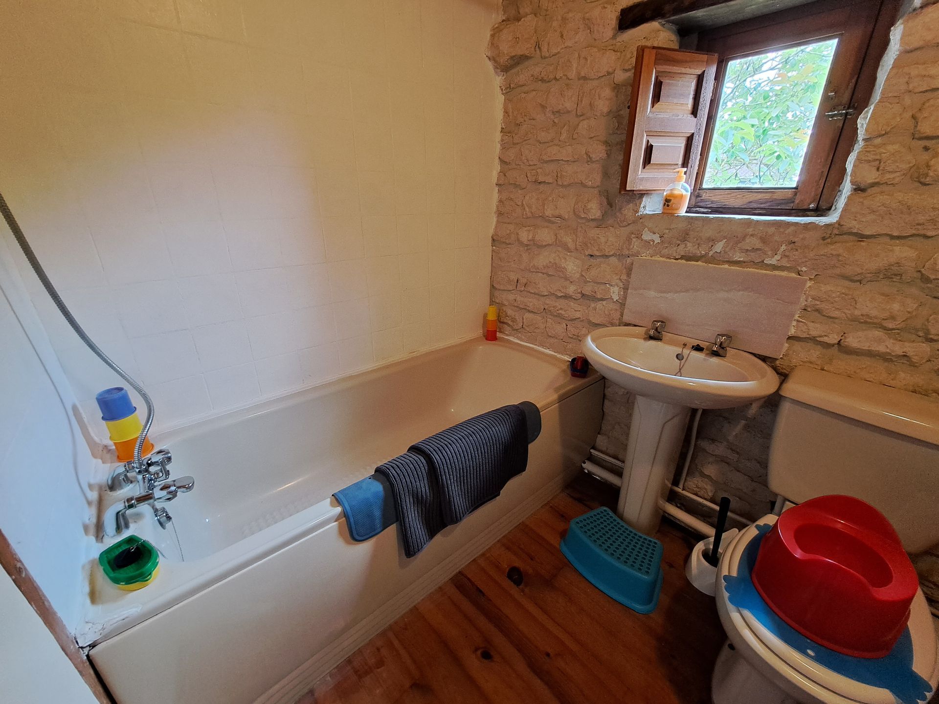 salle de bain avec murs en pierres apparentes avec baie vitrée de taille normale, lavabo et toilettes assortis