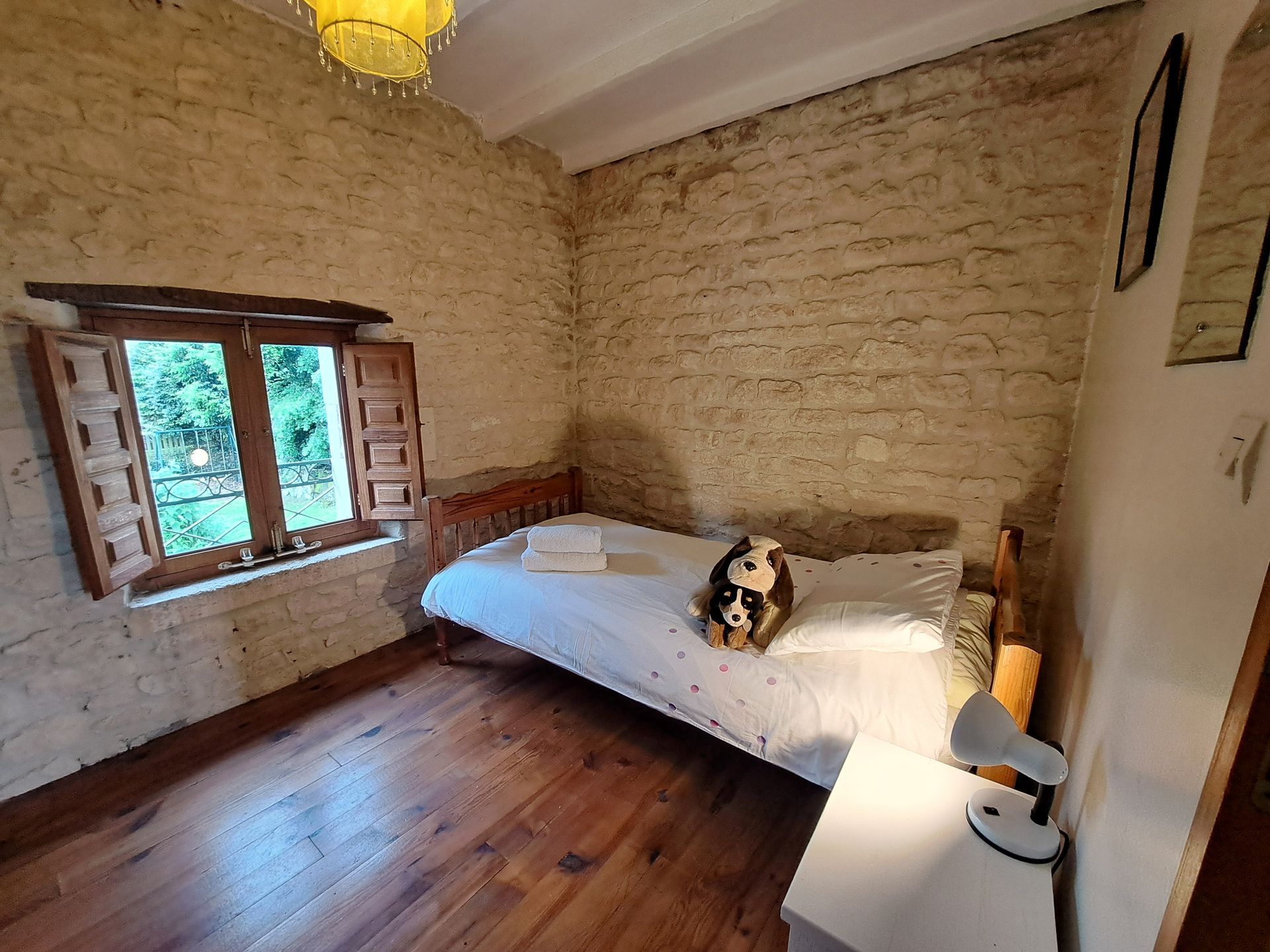 single bedroom with wooden floorboards and stone walls