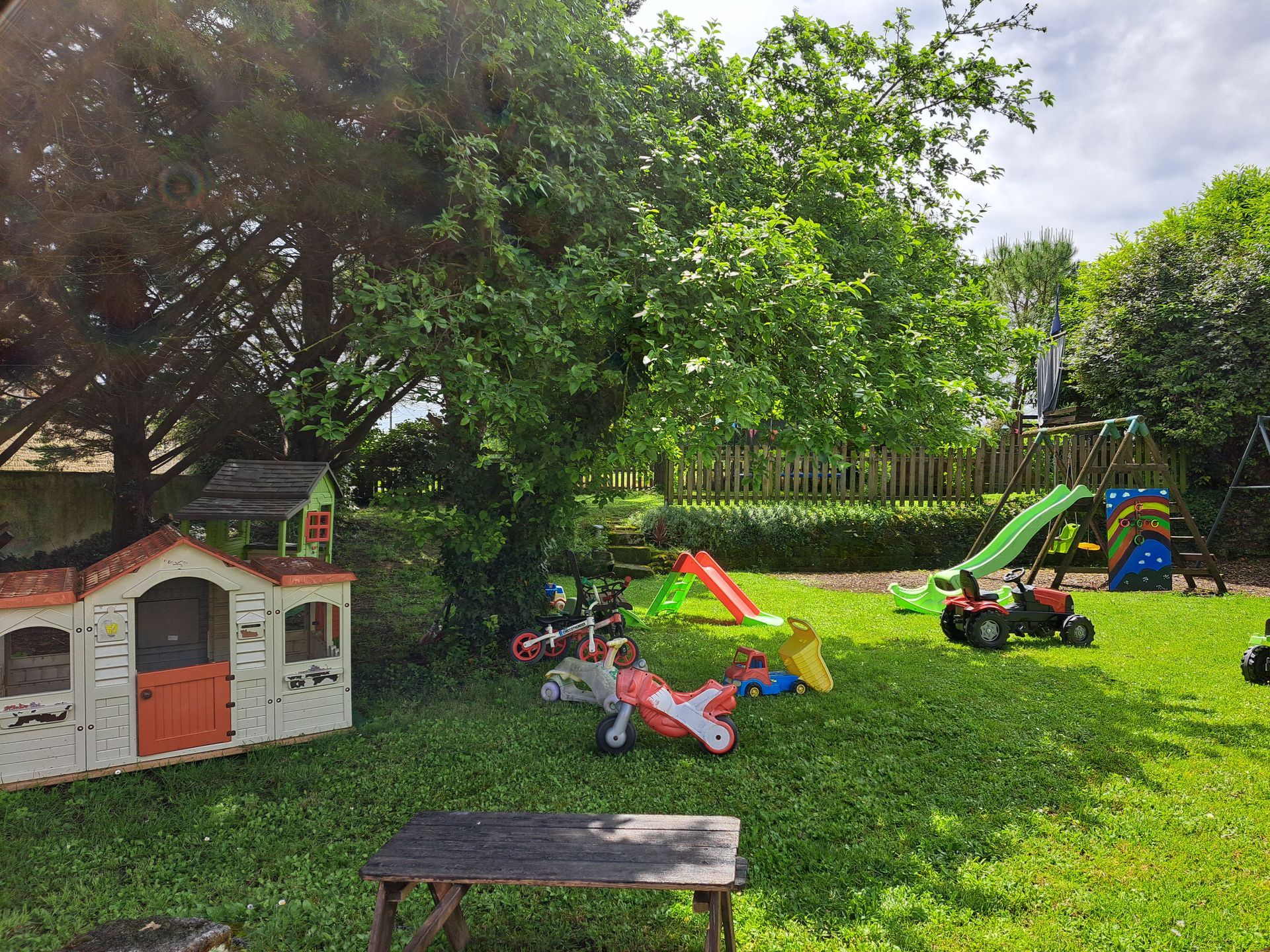 garden filled with childrens toys and a play house