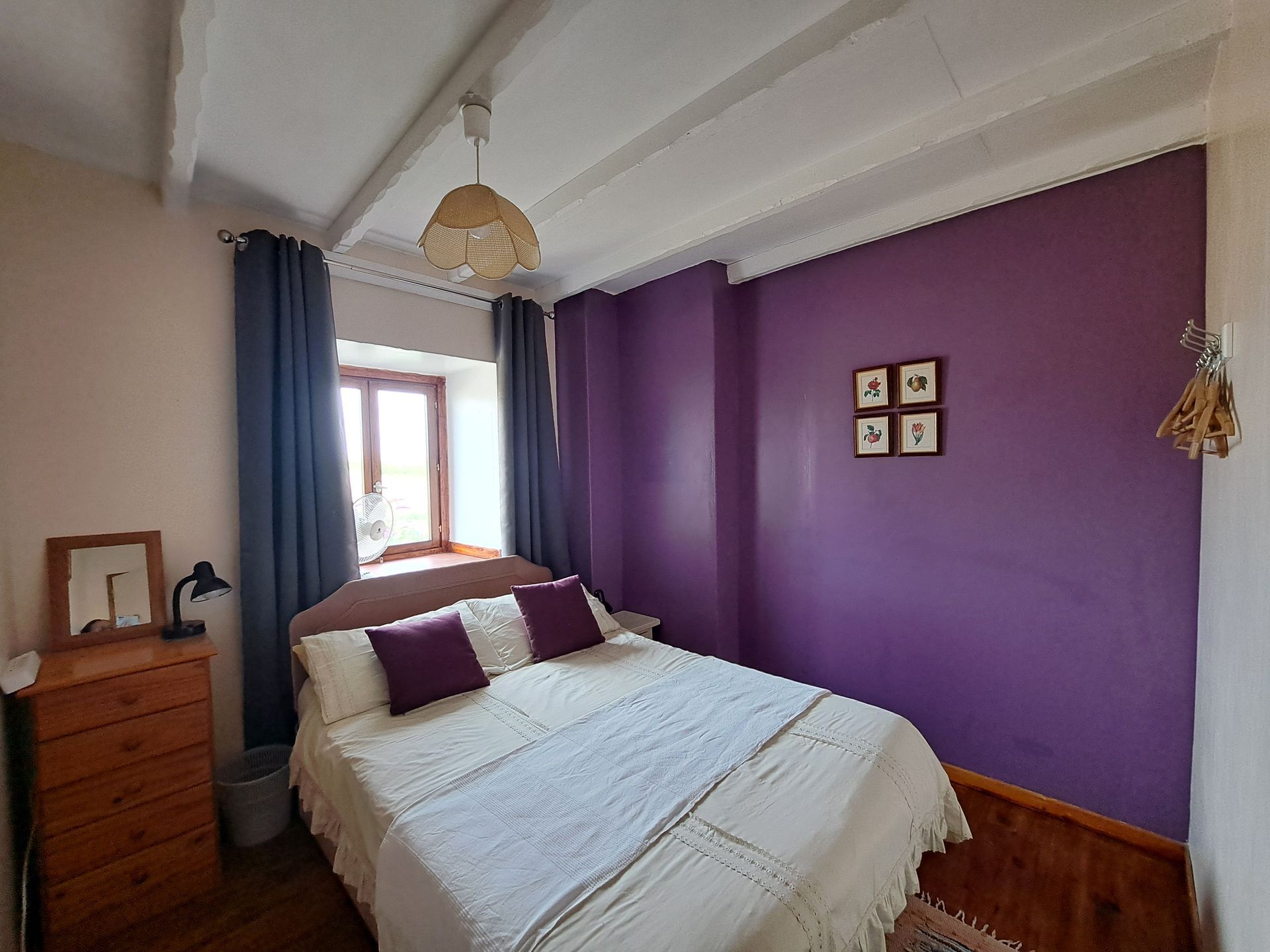 lit double avec coussins violets dans une chambre avec un mur violet caractéristique