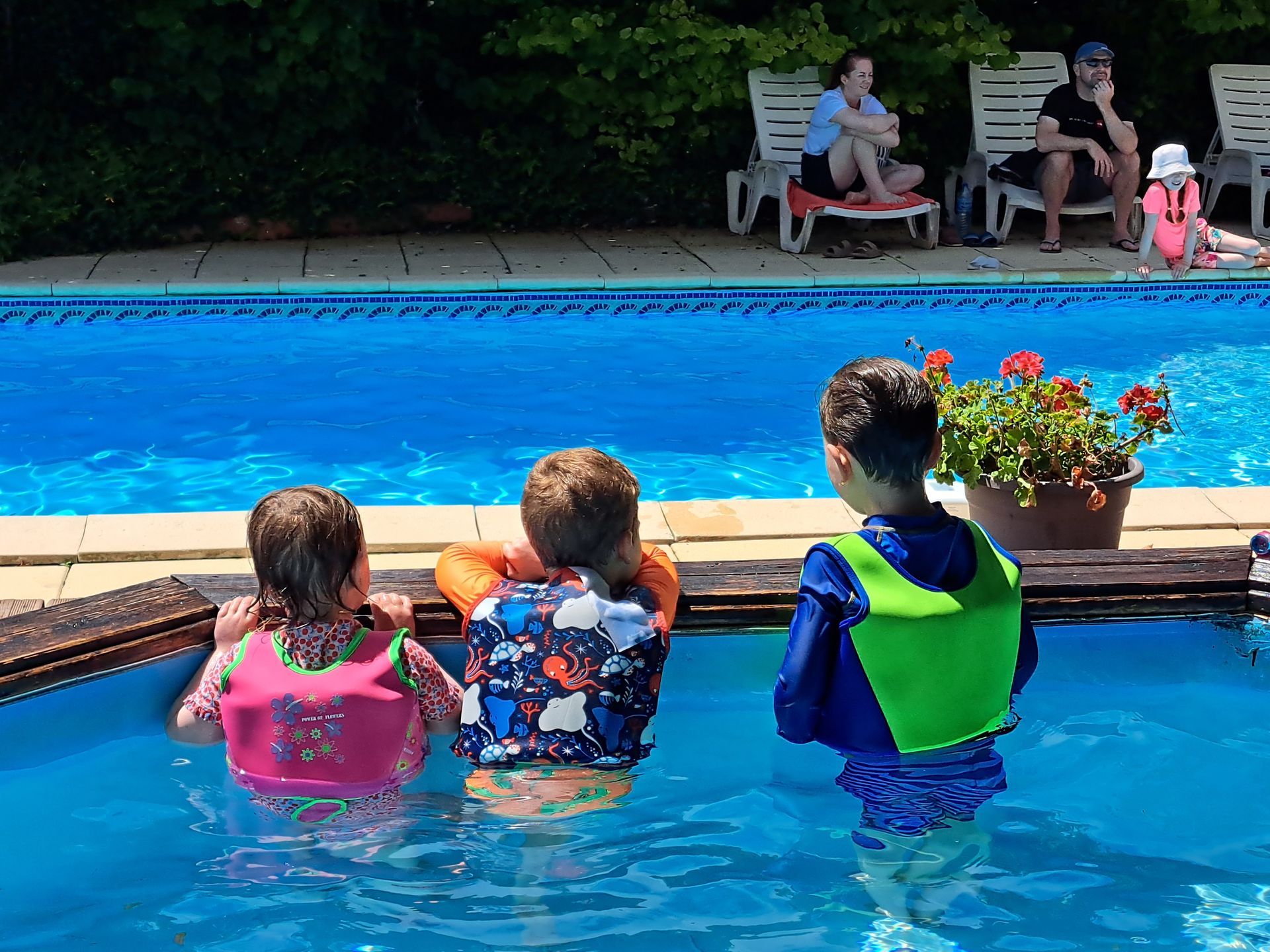 3 children looking over the edge of a pool