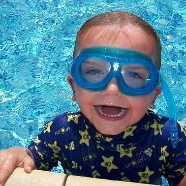 toddler in a pool with a big smile