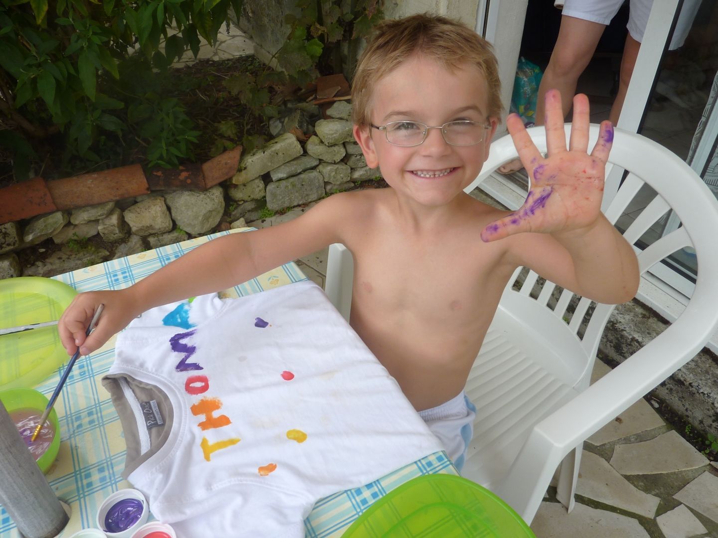 boy showing his hands with paint on as he paints a t-shirt