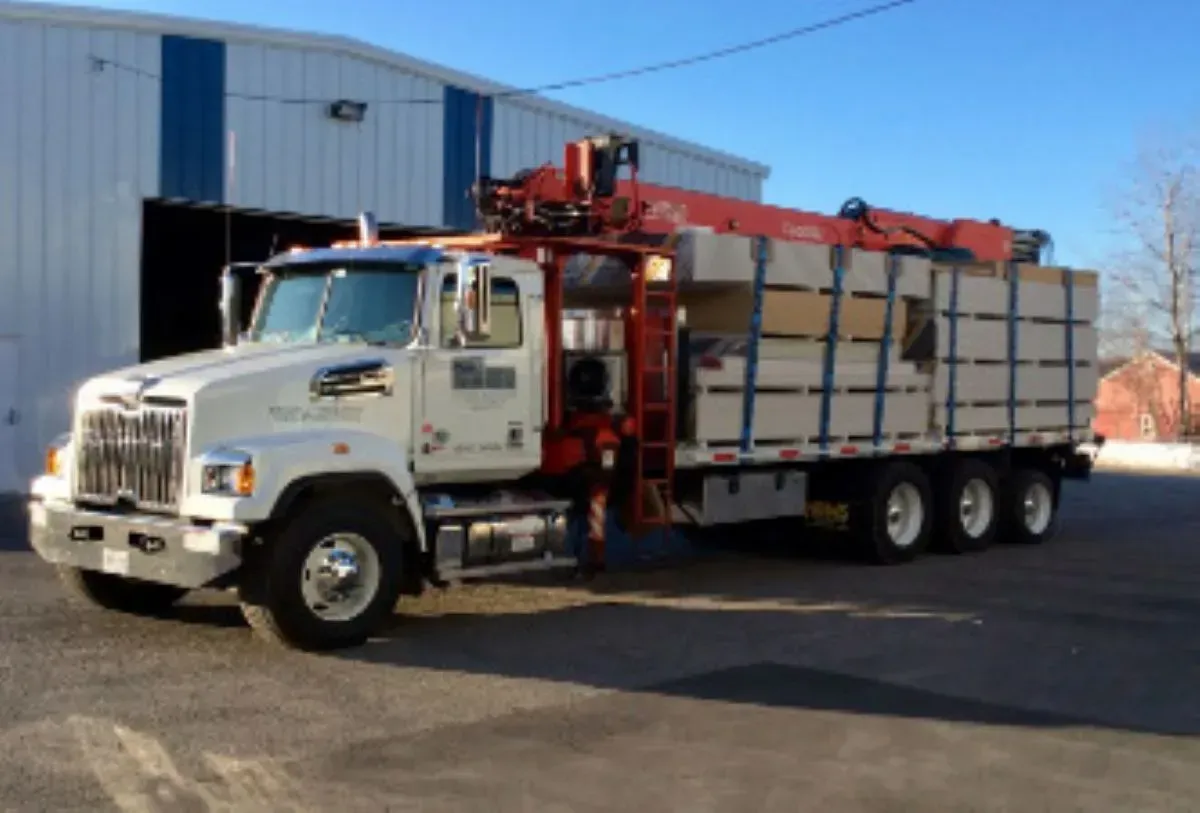A white truck with a red crane is parked in front of a building