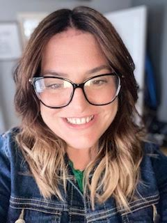 Head and shoulders photo of Ally, who has long dark hair and is wearing glasses.