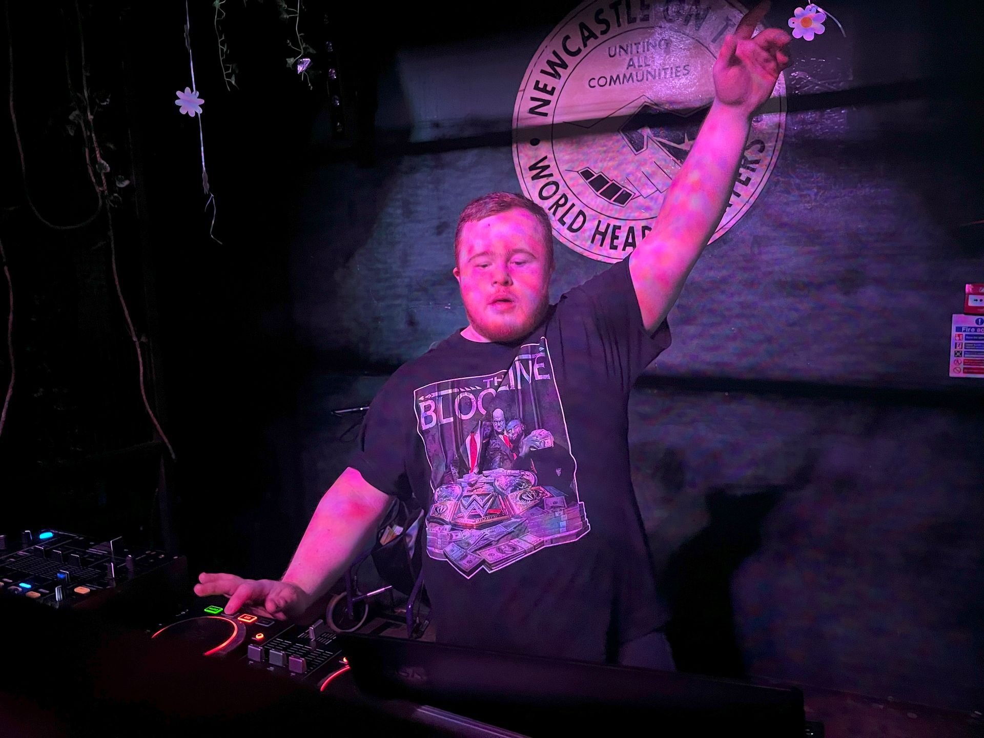 Man playing DJ decks with one arm raised