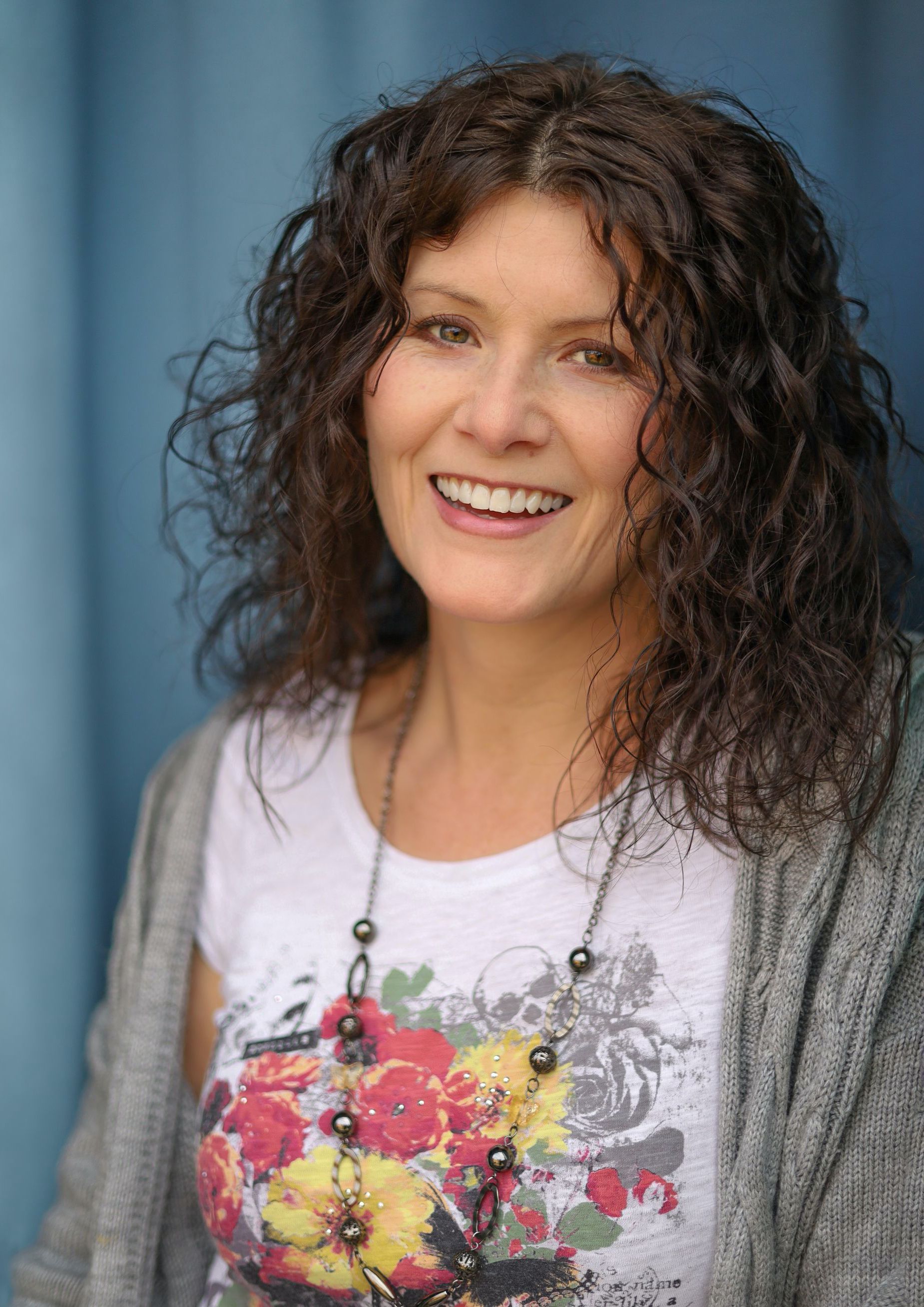 Photo of Cat, who has long dark hair and is wearing an orange top.