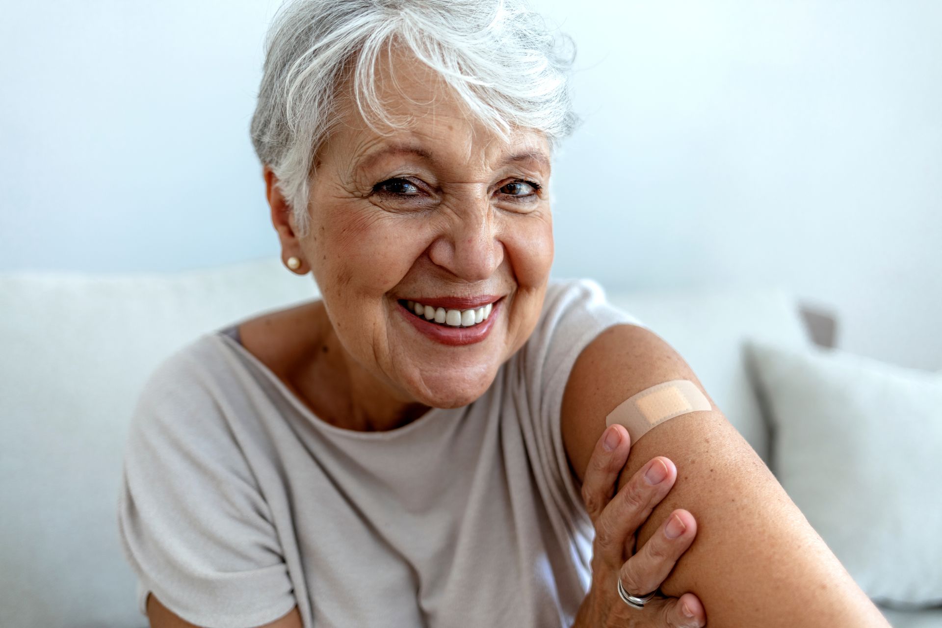 Smiling person with bandage on arm, suggesting vaccination.