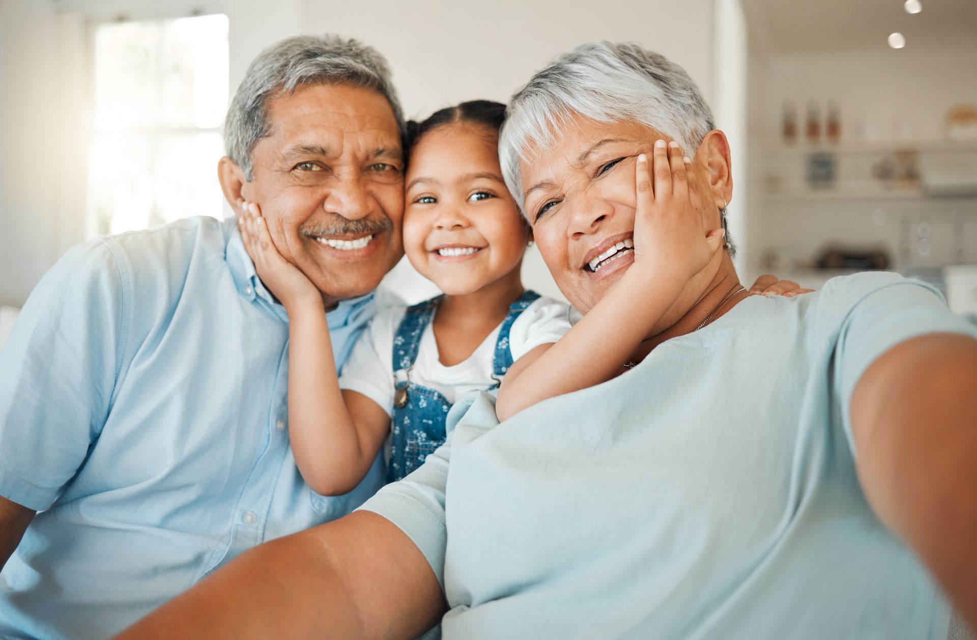 Grandparents and child smiling, close-up. They are indoors. 