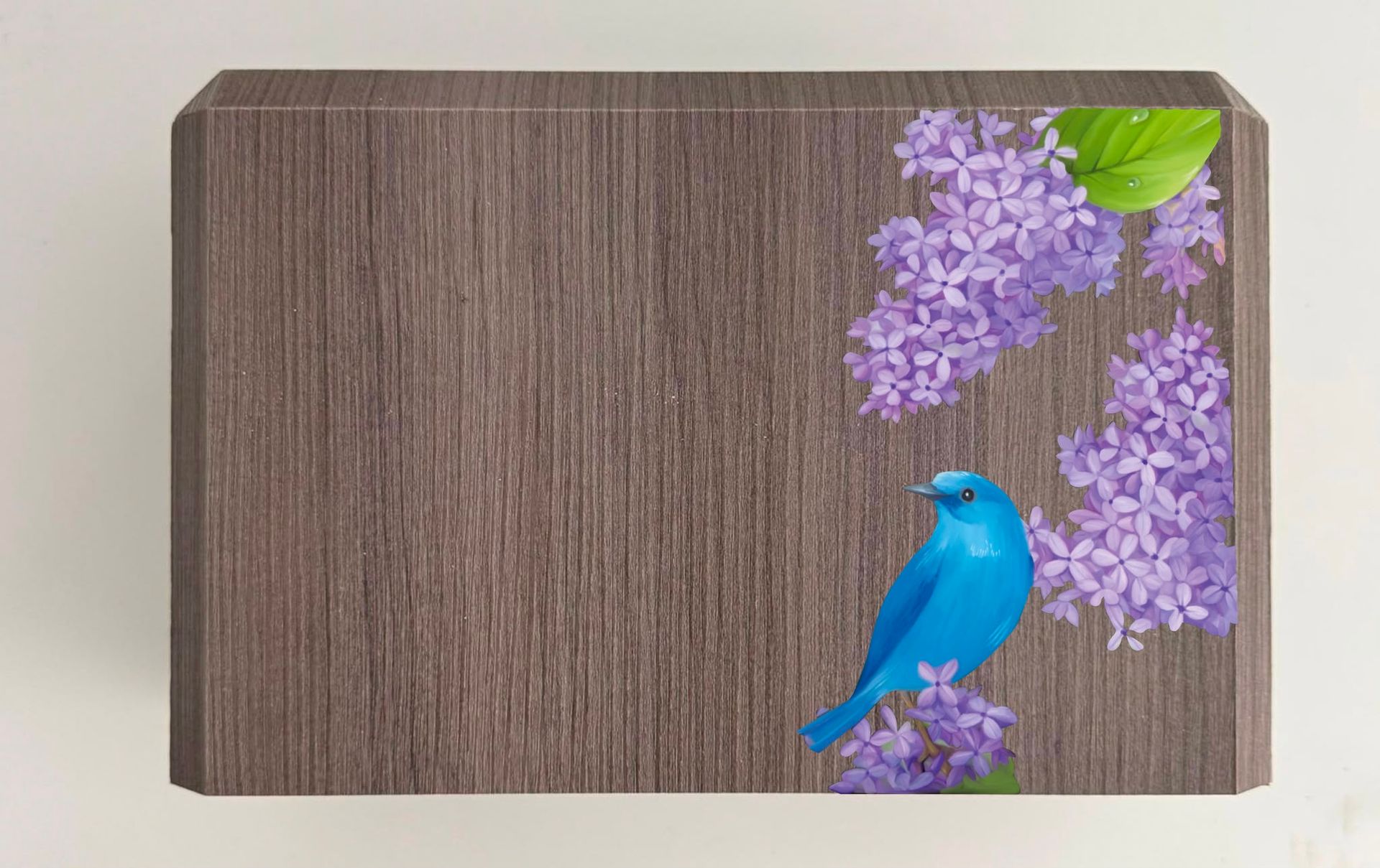 Vassoio di legno con un uccellino blu appollaiato su fiori viola e una foglia verde nell’angolo