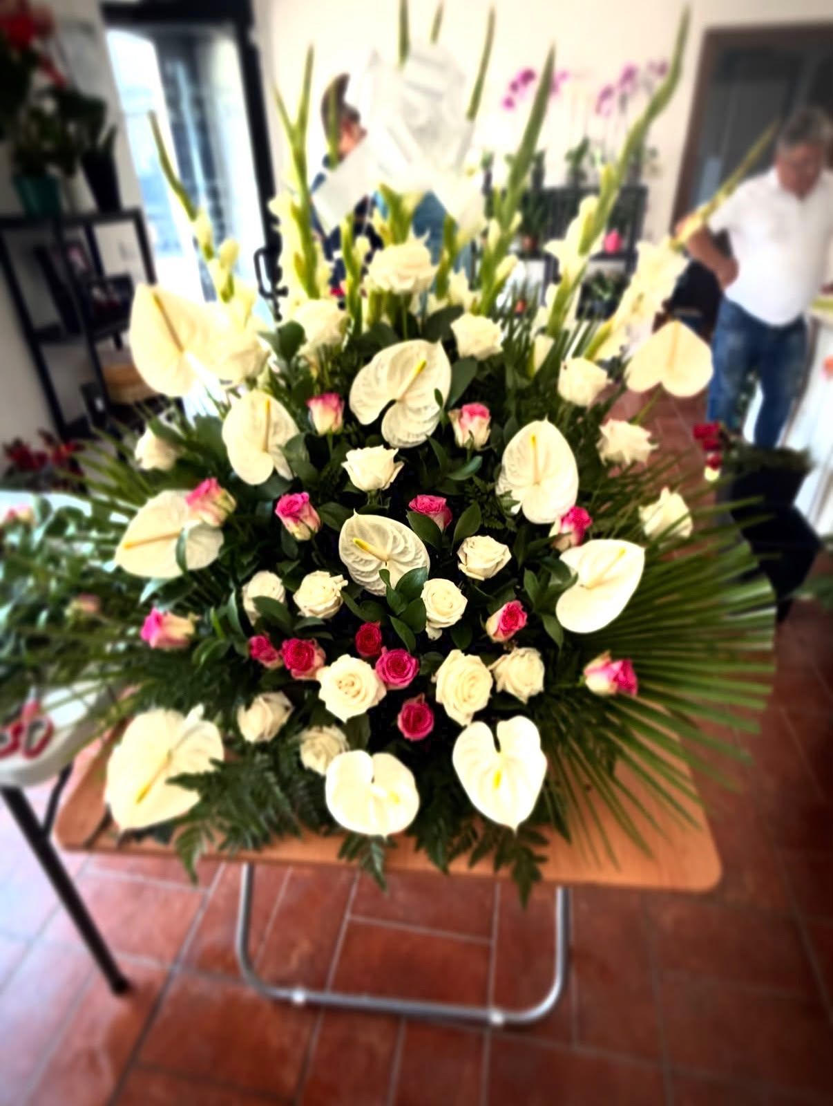 Grande composizione floreale con fiori bianchi e rosa su un tavolo, al chiuso