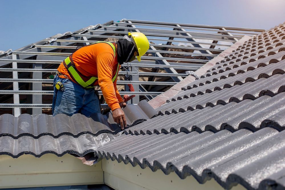 Roofer in Orange Safety Gear Installing Gray Tiles on a Rooftop — CP Roofing in Old Bar, NSW