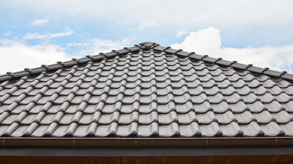 Brown Tile Roof Against a Cloudy Blue Sky — CP Roofing in Old Bar, NSW