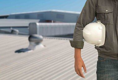 Man Wearing a Hard Hat is Standing on a Roof — CP Roofing in Taree, NSW