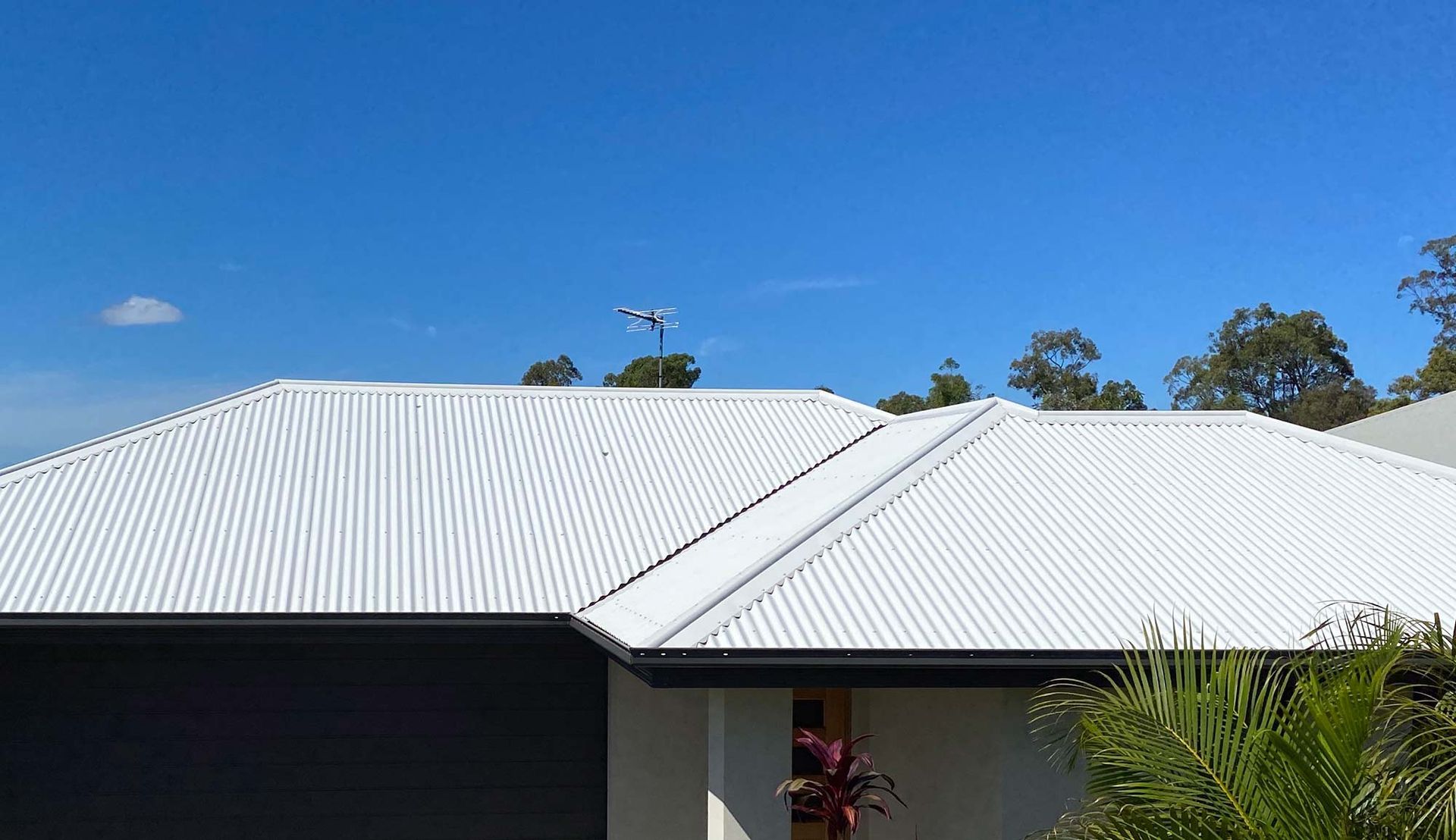 House With a White Roof and a Blue Sky in the Background — CP Roofing in Wingham, NSW