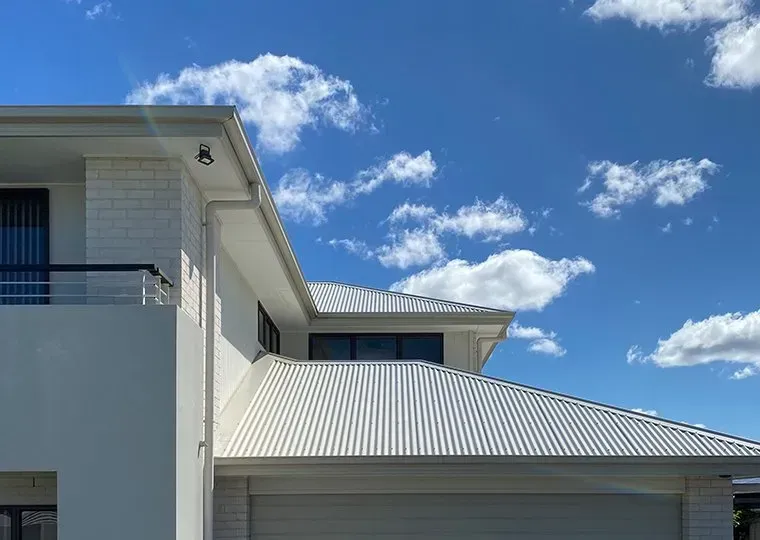 White House With a White Roof and a Blue Sky in the Background — CP Roofing in Wingham, NSW
