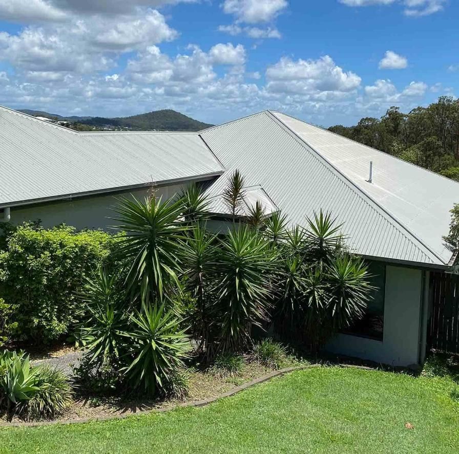 House With a White Roof is Surrounded by Trees and Bushes — CP Roofing in Old Bar, NSW