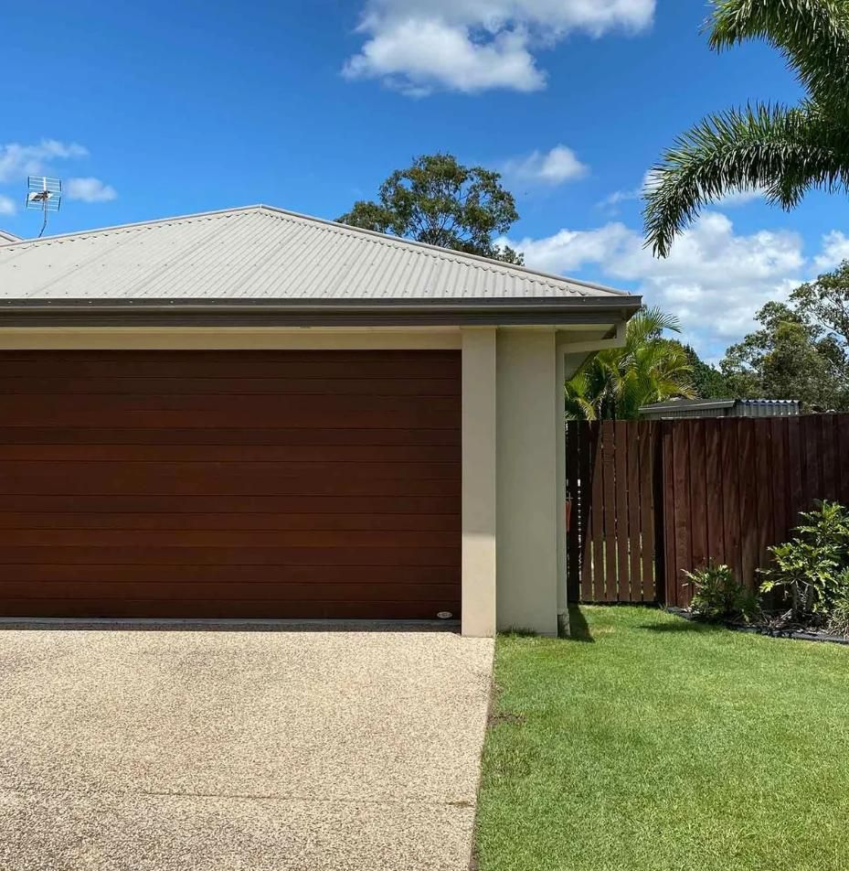 House With a Wooden Garage Door and a Gravel Driveway — CP Roofing in Wingham, NSW