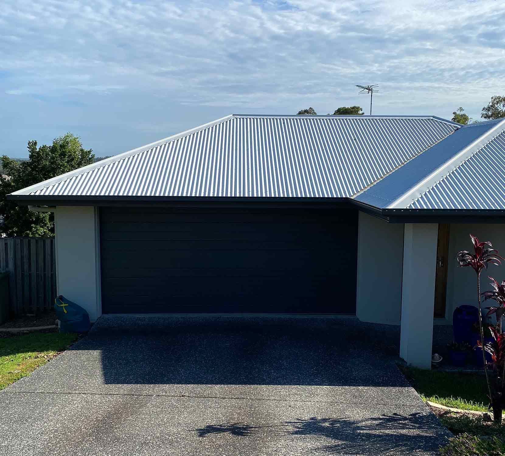 White House With a Black Garage Door and a White Roof — CP Roofing in Taree, NSW
