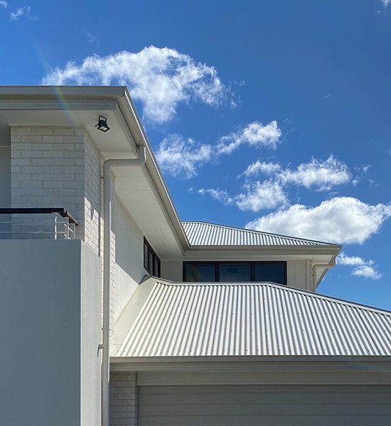 White House With a White Roof and a Blue Sky in the Background — CP Roofing in Old Bar, NSW