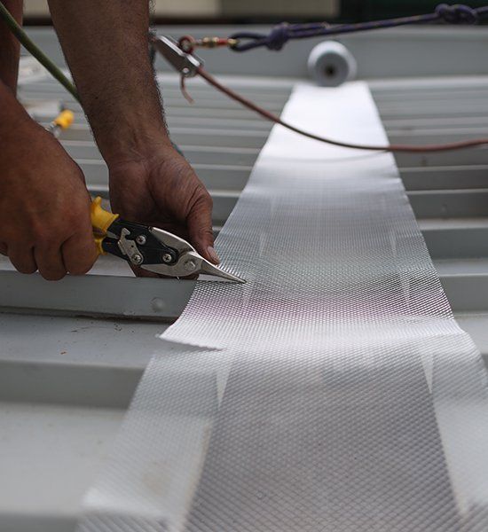 Person is Cutting a Piece of Metal With a Pair of Scissors — CP Roofing in Forster, NSW