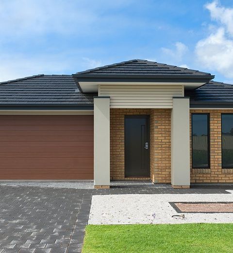 Brick House With a Black Roof and a Brown Garage Door — CP Roofing in Old Bar, NSW