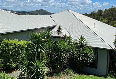 White House With a White Roof is Surrounded by Trees and Bushes — CP Roofing in Old Bar, NSW