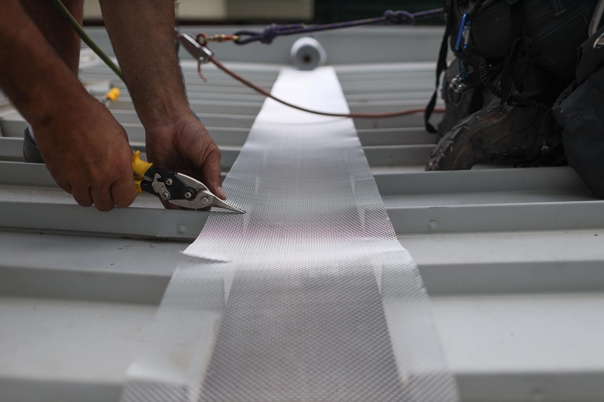 Man is Working on a Roof With a Pair of Pliers — CP Roofing in Gloucester, NSW