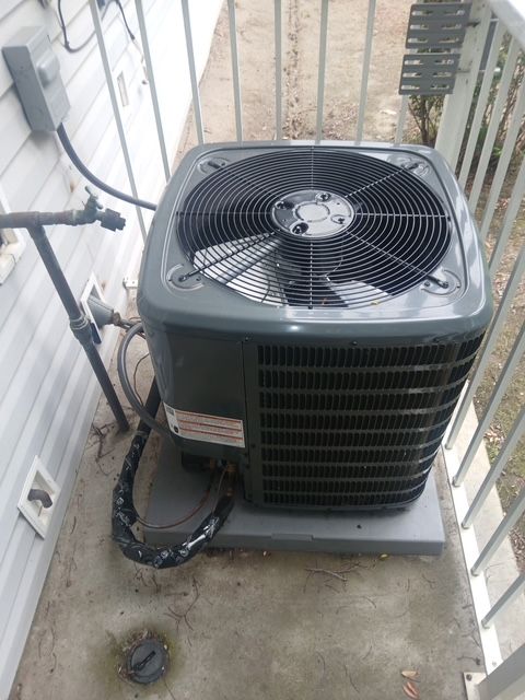 Outdoor air conditioner unit on a narrow balcony beside railings and walls