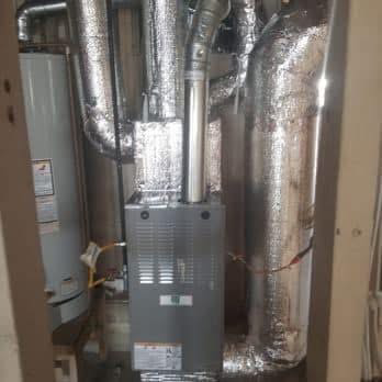 HVAC furnace with silver insulated ductwork in a utility closet
