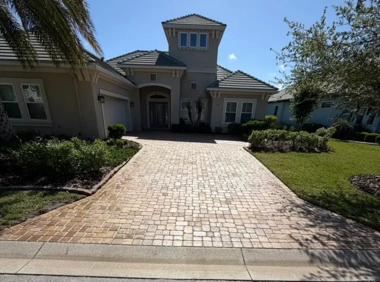 Palm Coast's #1 Paver Sealing Experts A driveway with perfectly sealed pavers leading to a two-story house in Grand Haven in Palm Coast, Flagler County, FL.