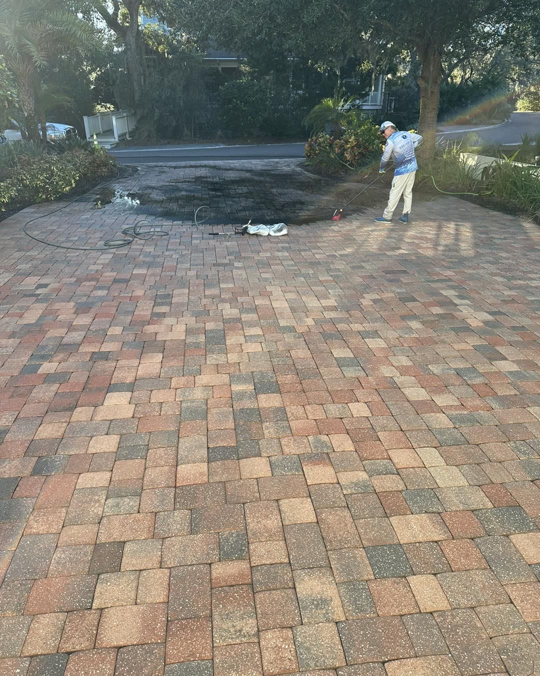 Brick driveway with a person standing near a wooded road and a small fallen tree branch.