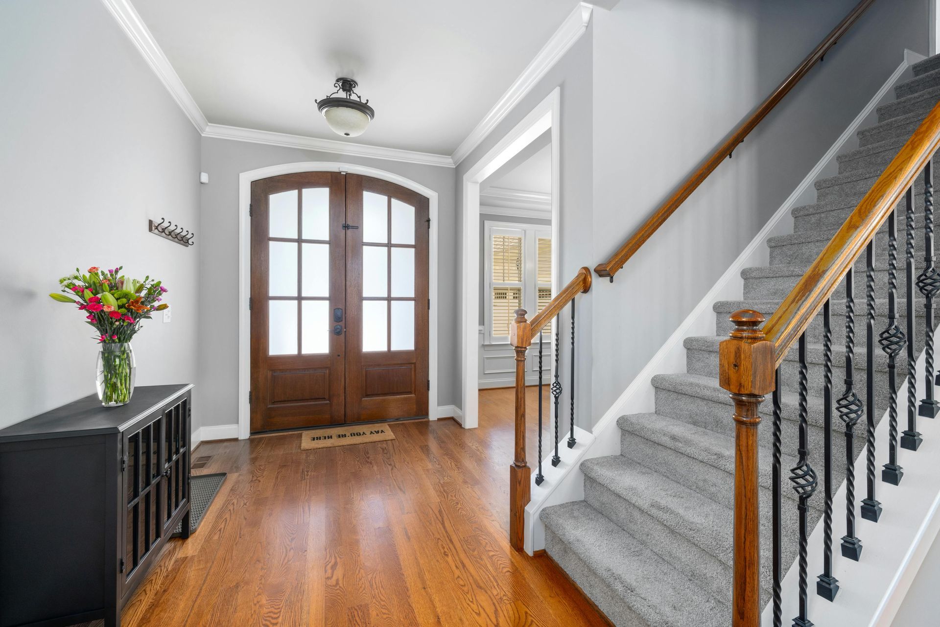 A hallway with hardwood floors and stairs in a house.