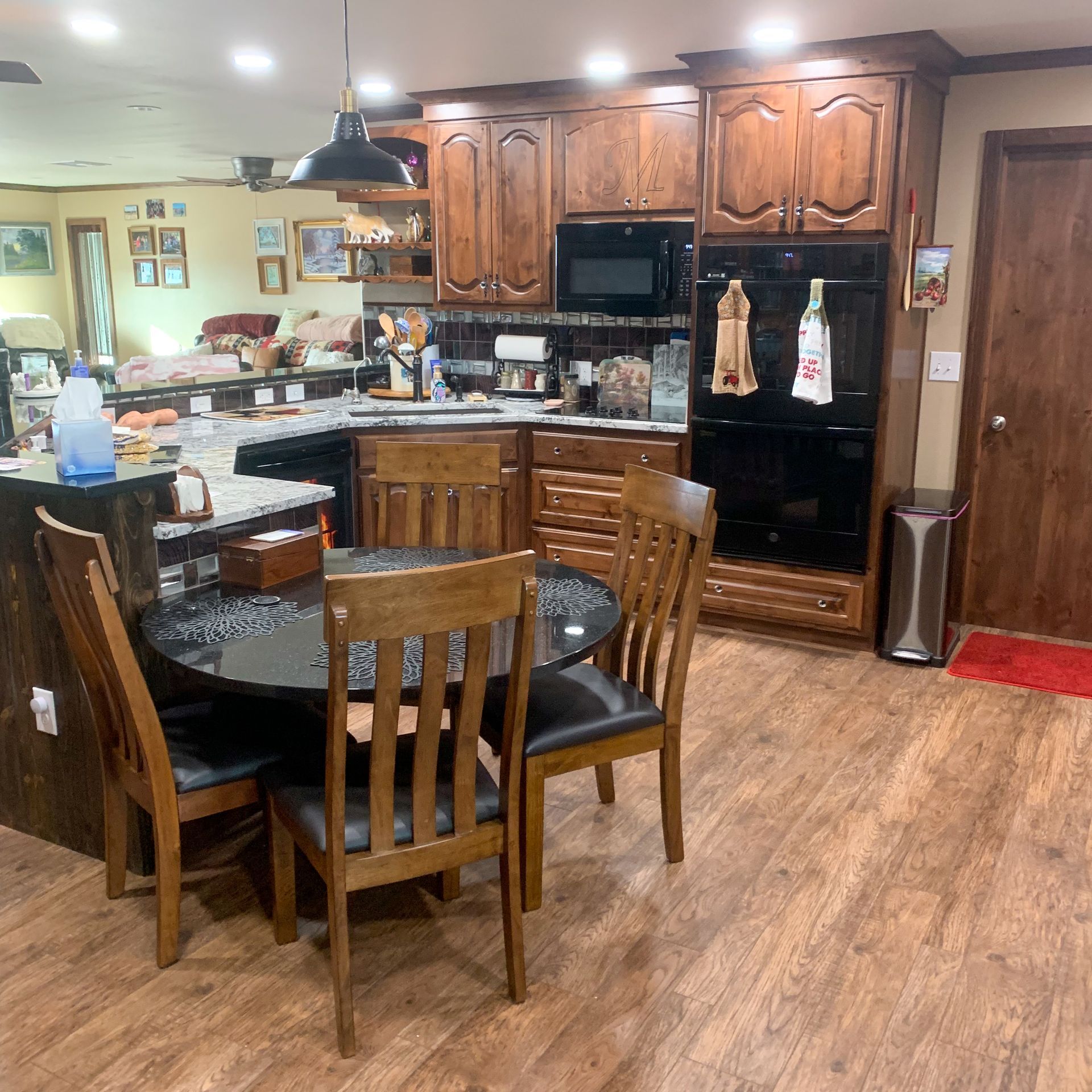 Kitchen with dark wood cabinets, black appliances, and a table with chairs.