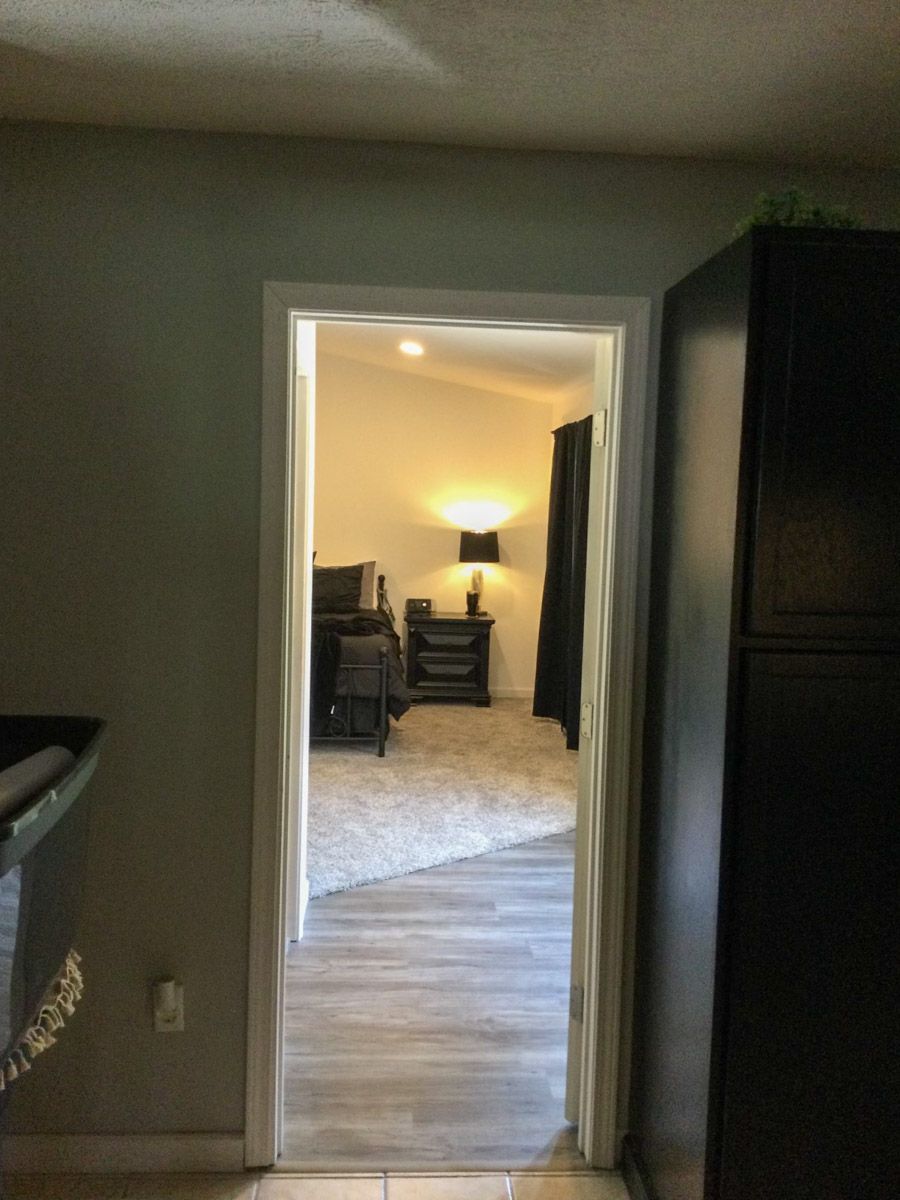 Doorway looking into a bedroom with a bed, nightstand, and lamp.
