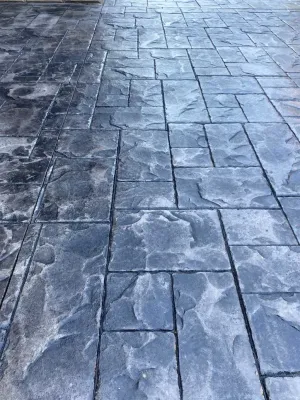 A close up of a concrete driveway with a brick pattern.
