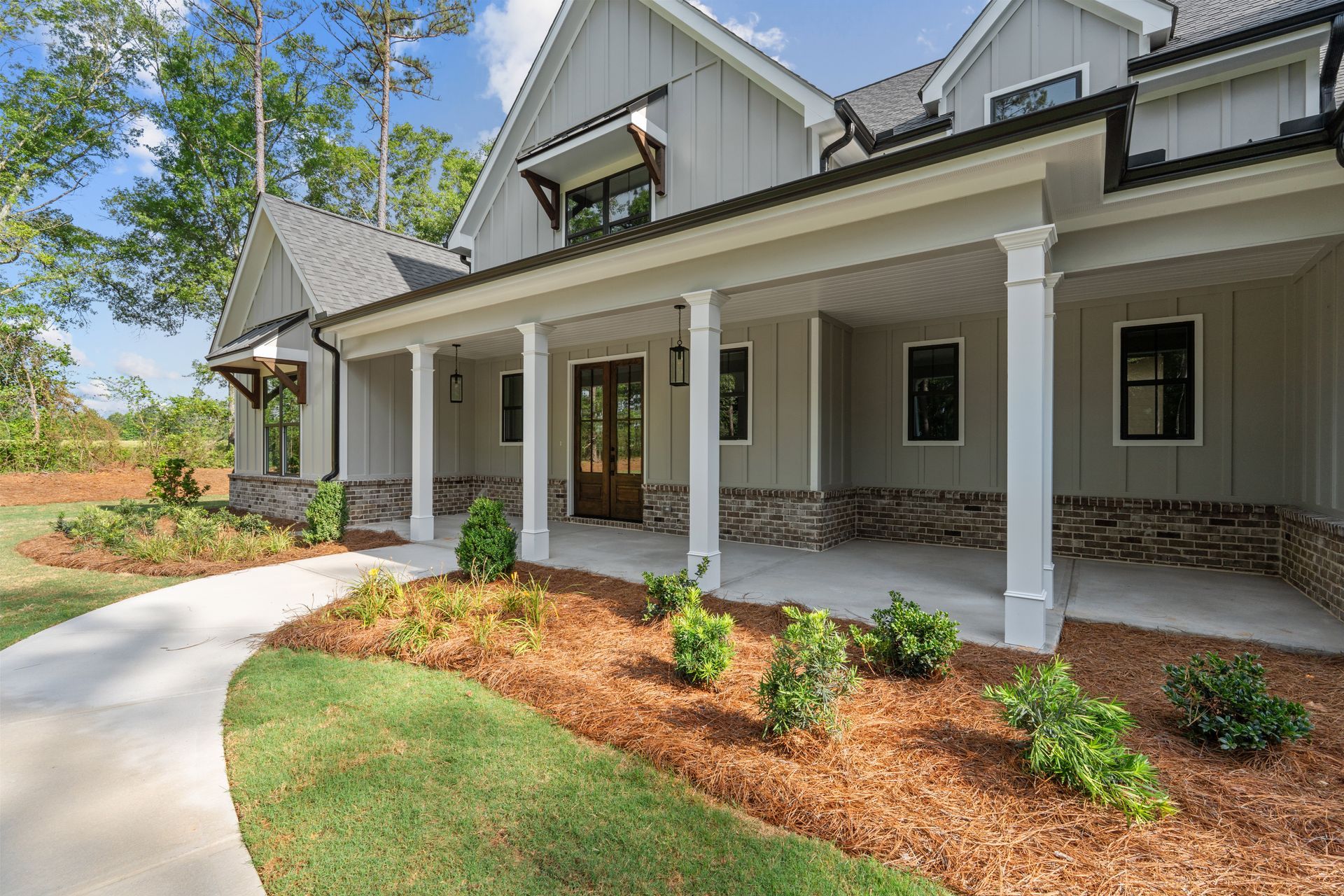 Modern house exterior with a covered porch, white columns, and landscaped front walkway
