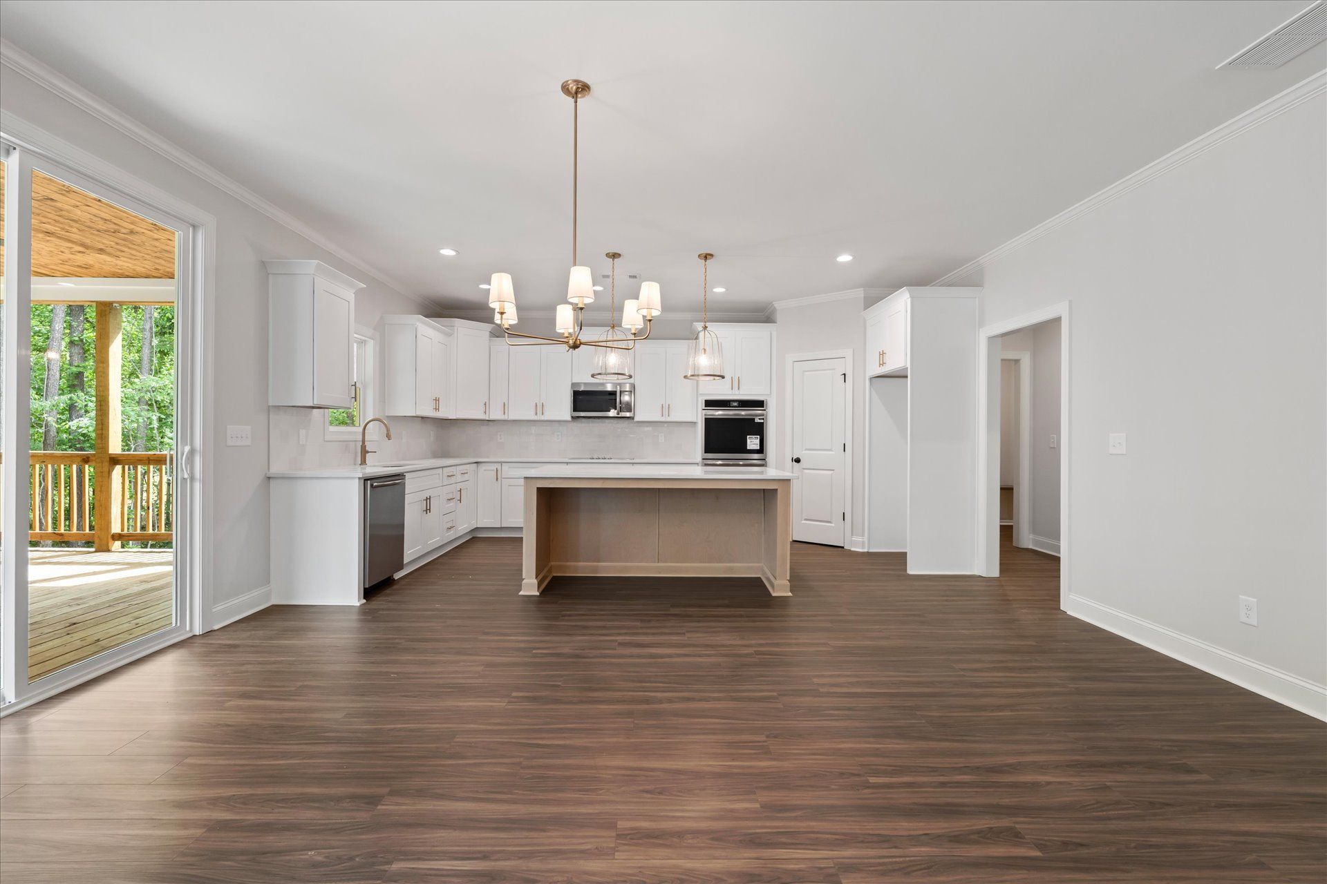 Bright modern kitchen with white cabinets, island, pendant lights, and wood floors, open to a patio.