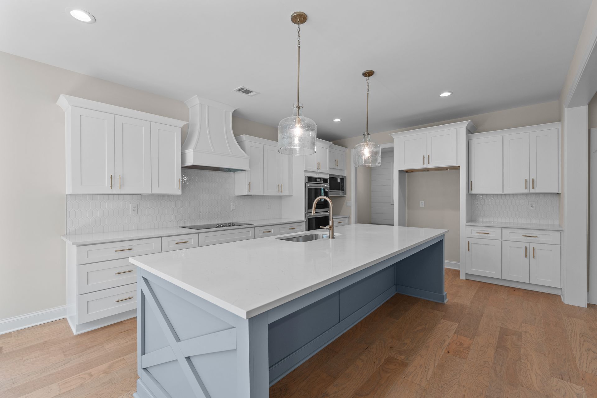 Bright modern white kitchen with large island, gray countertops, and wood floors