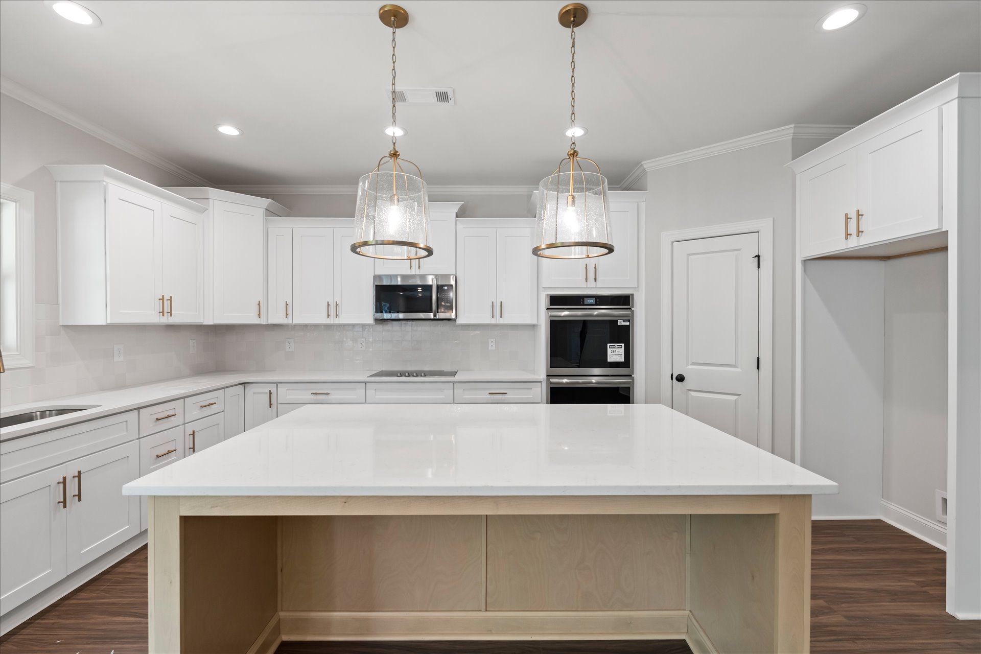 Modern white kitchen with island, pendant lights, built-in oven, and dark wood flooring