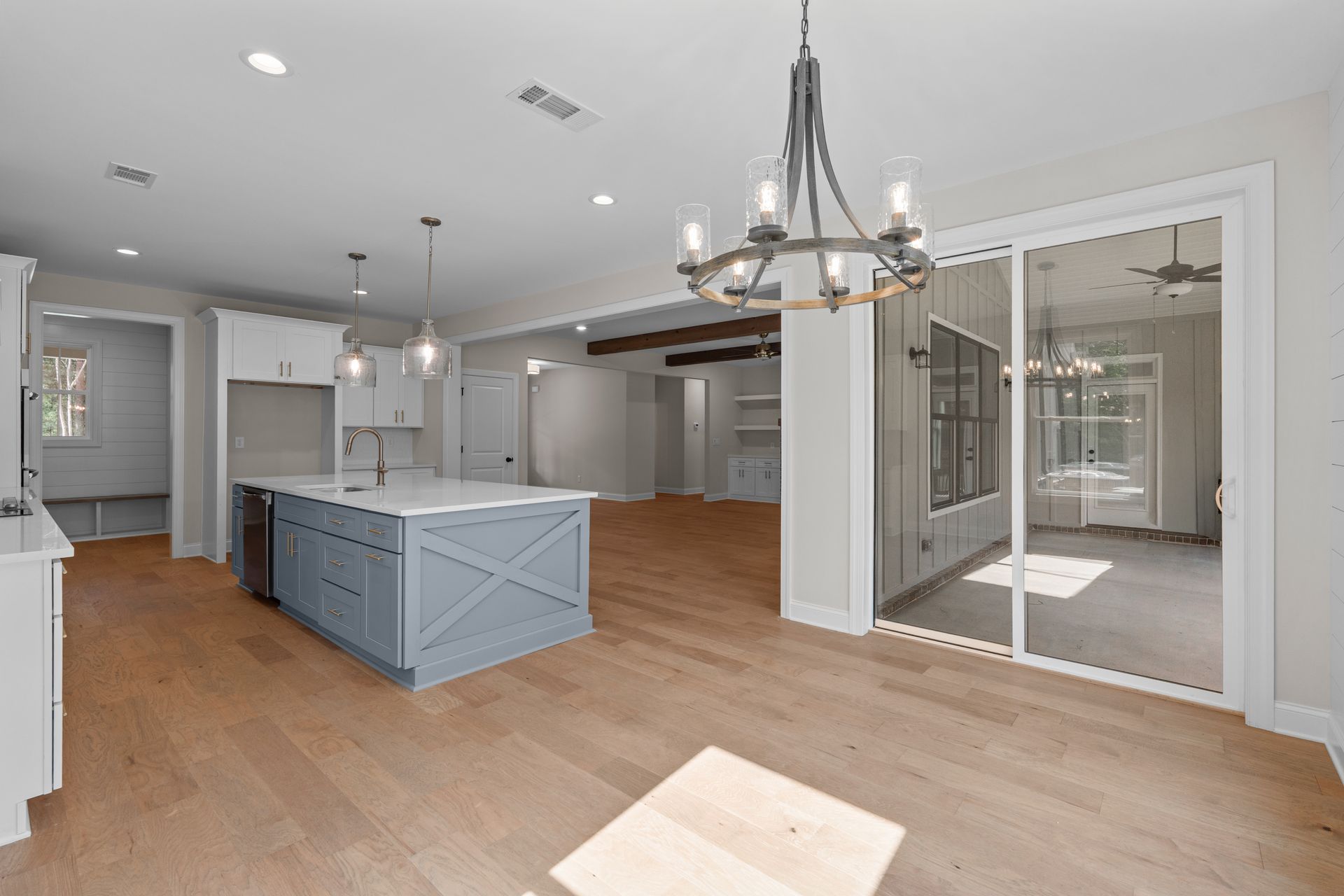 Open-concept kitchen and dining area with blue island, hardwood floors, and sliding glass doors.