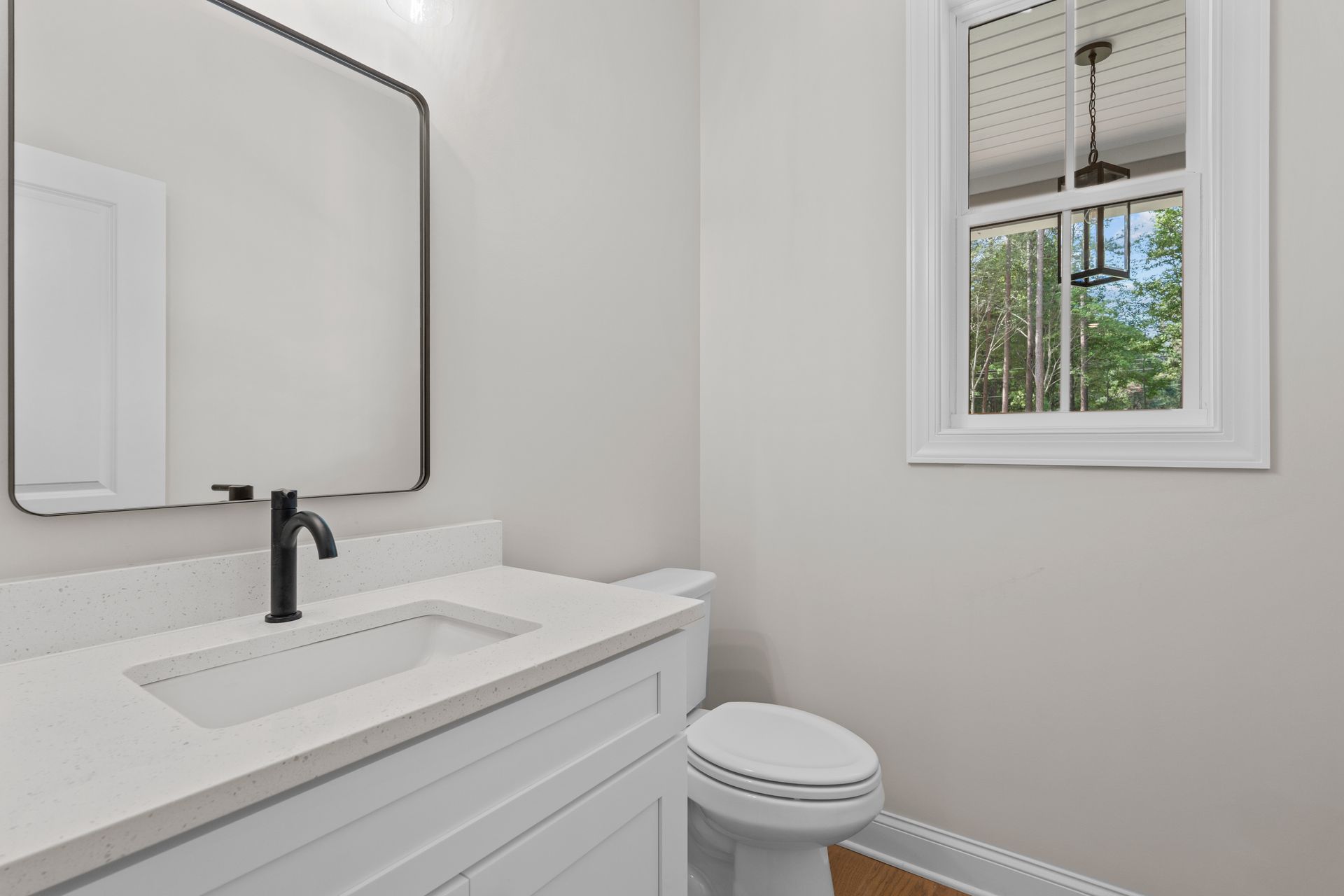 Modern white bathroom with vanity, mirror, and small window.
